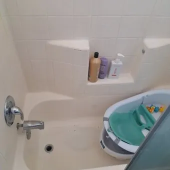 The same bathtub and tile surround clean, with the same toiletries on the shelf