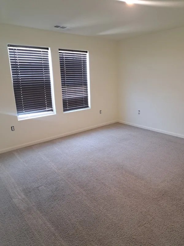 Empty carpeted bedroom with two windows