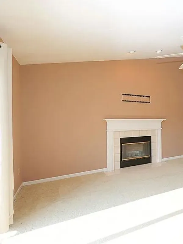 Empty living room with a fireplace and ceiling fan