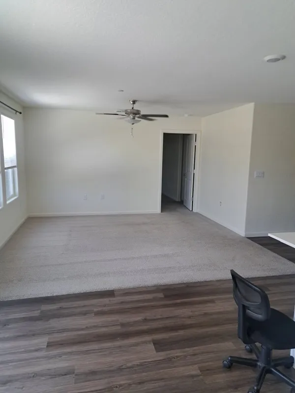 Empty room with a ceiling fan and wood-look floor