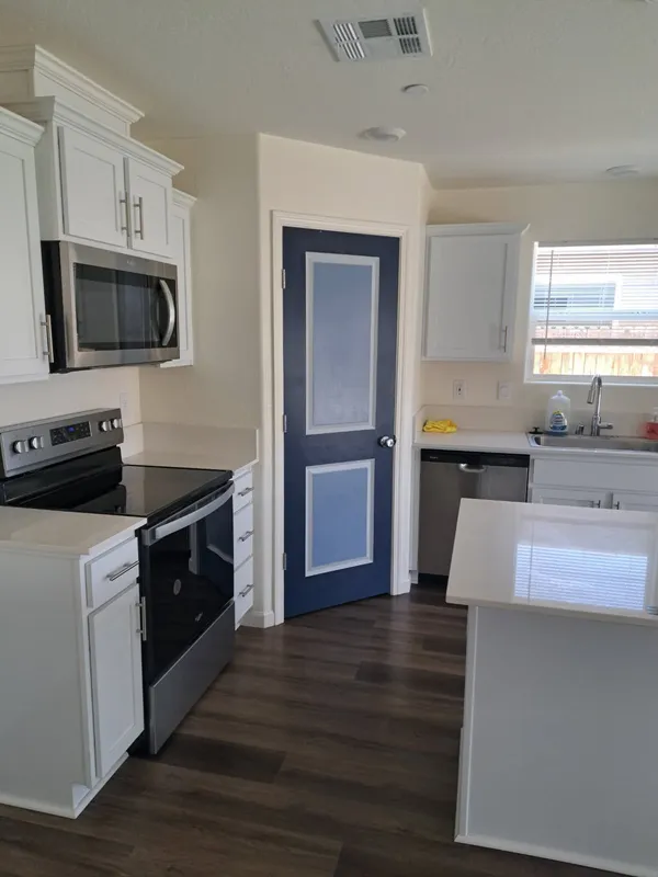 Kitchen with a stainless range beside a navy pantry door