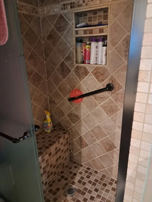 Tiled walk-in shower with a built-in bench and niche